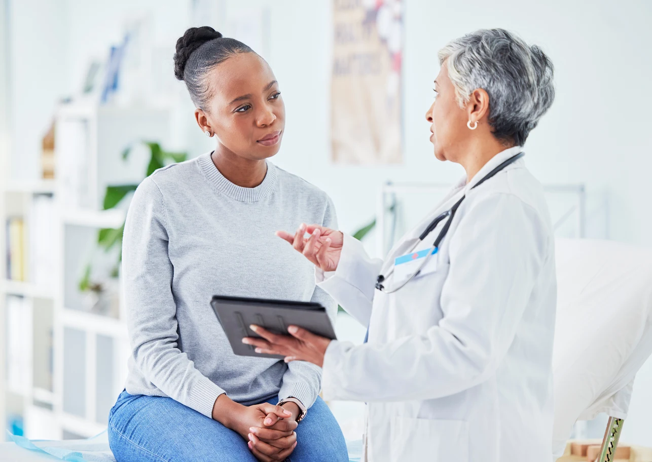 Doctor consulting a young female patient using a tablet.