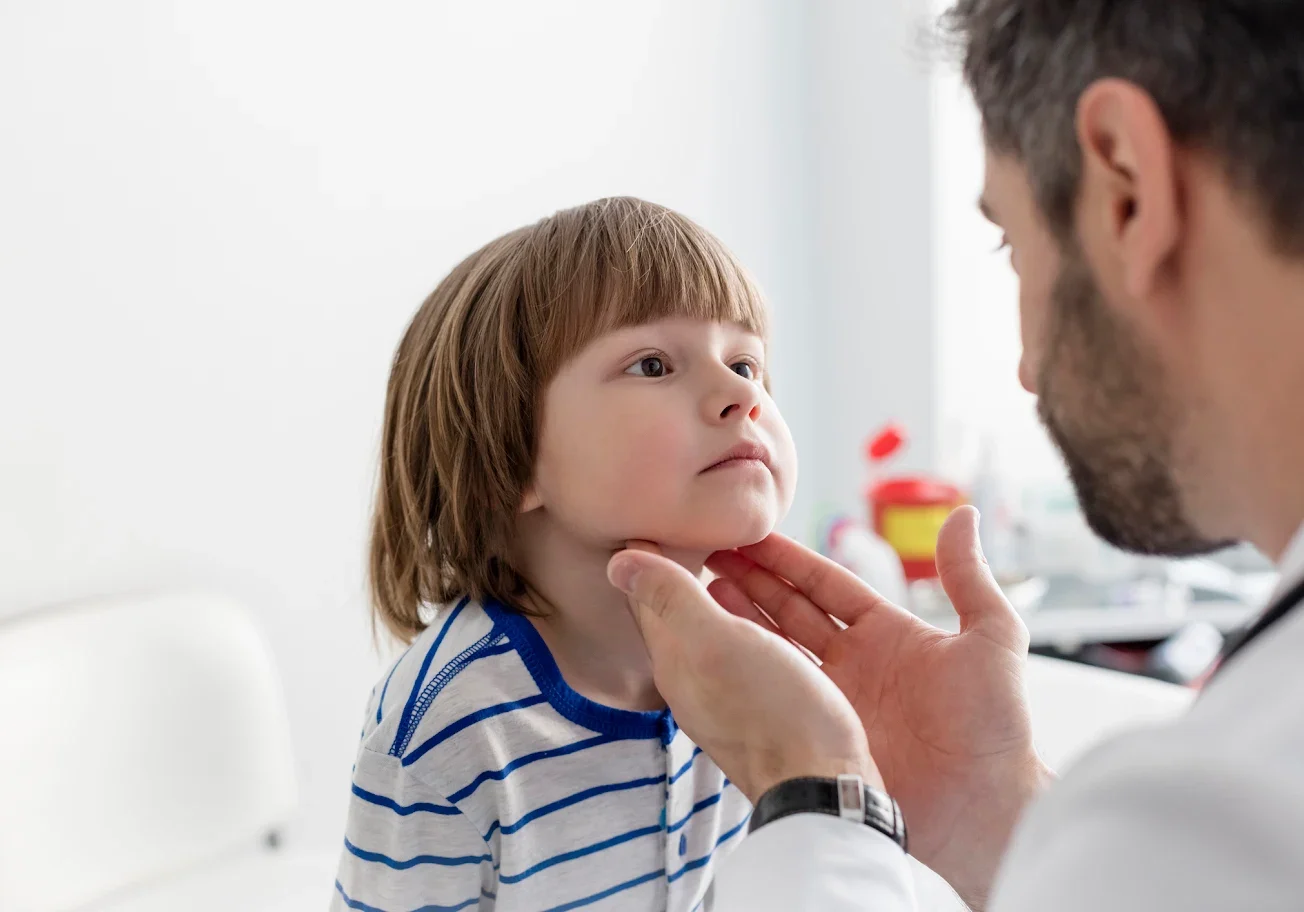 Doctor examining a young boy's throat carefully.