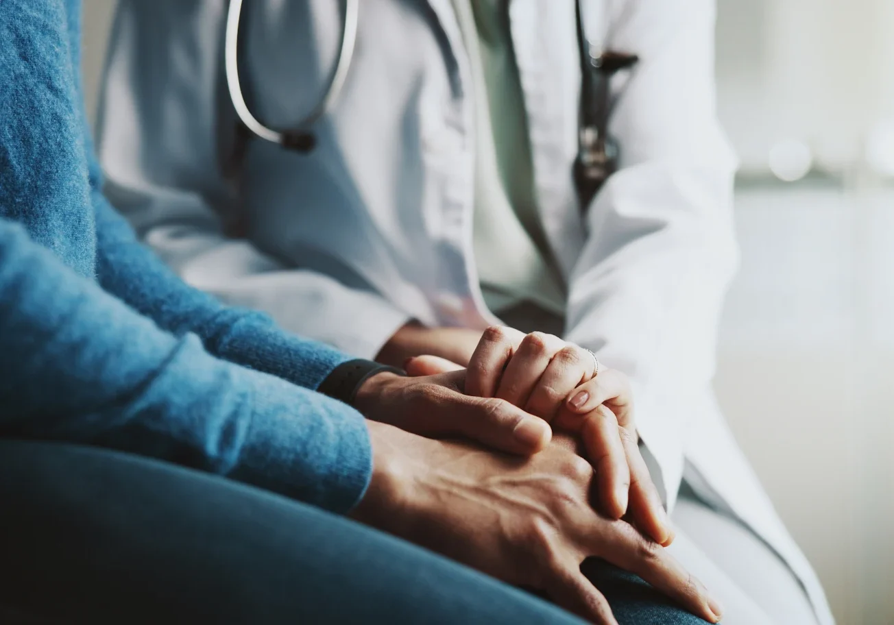 A doctor comforting a patient by holding their hands.